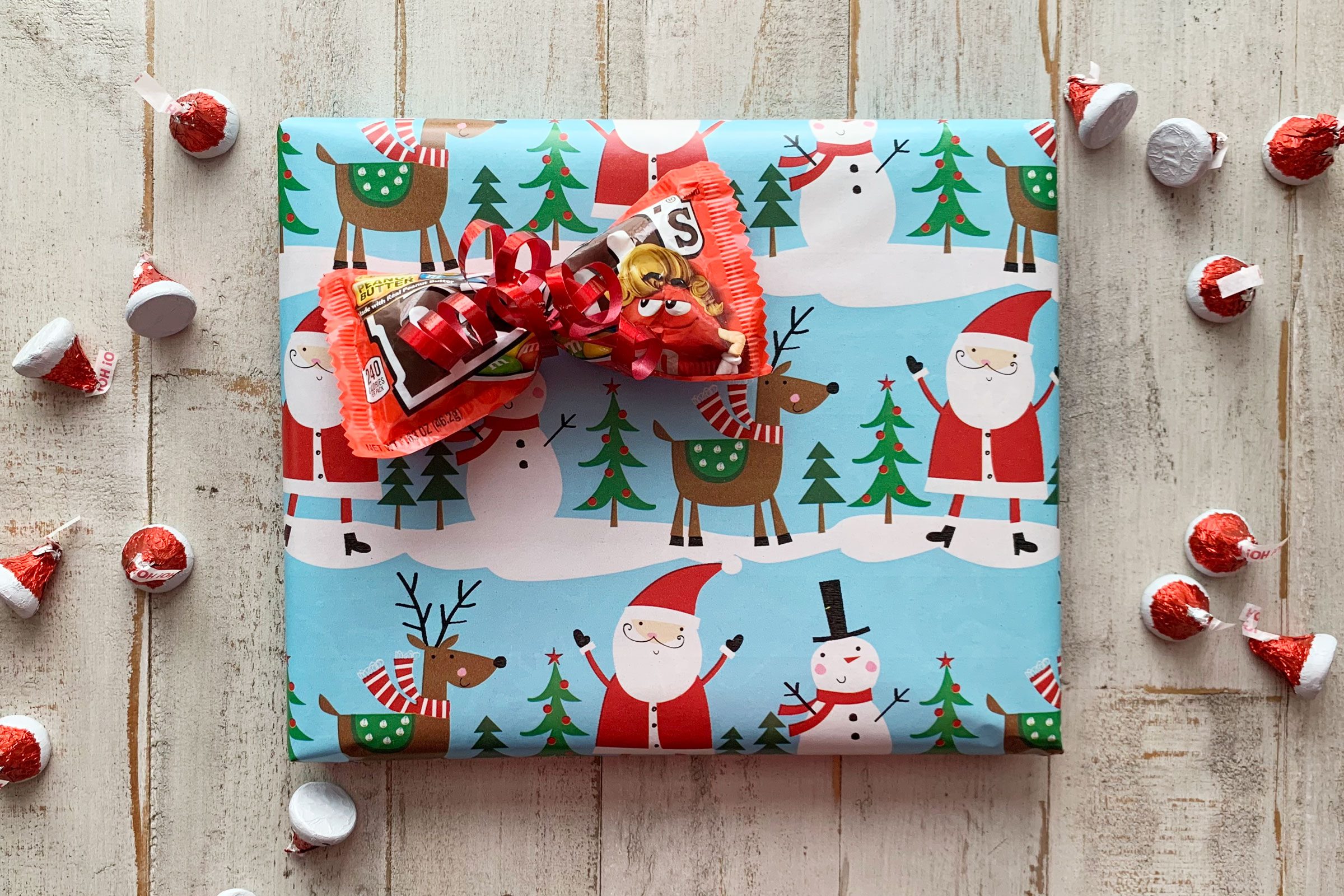 wrapped christmas gift with a pack of m&ms made into a bow