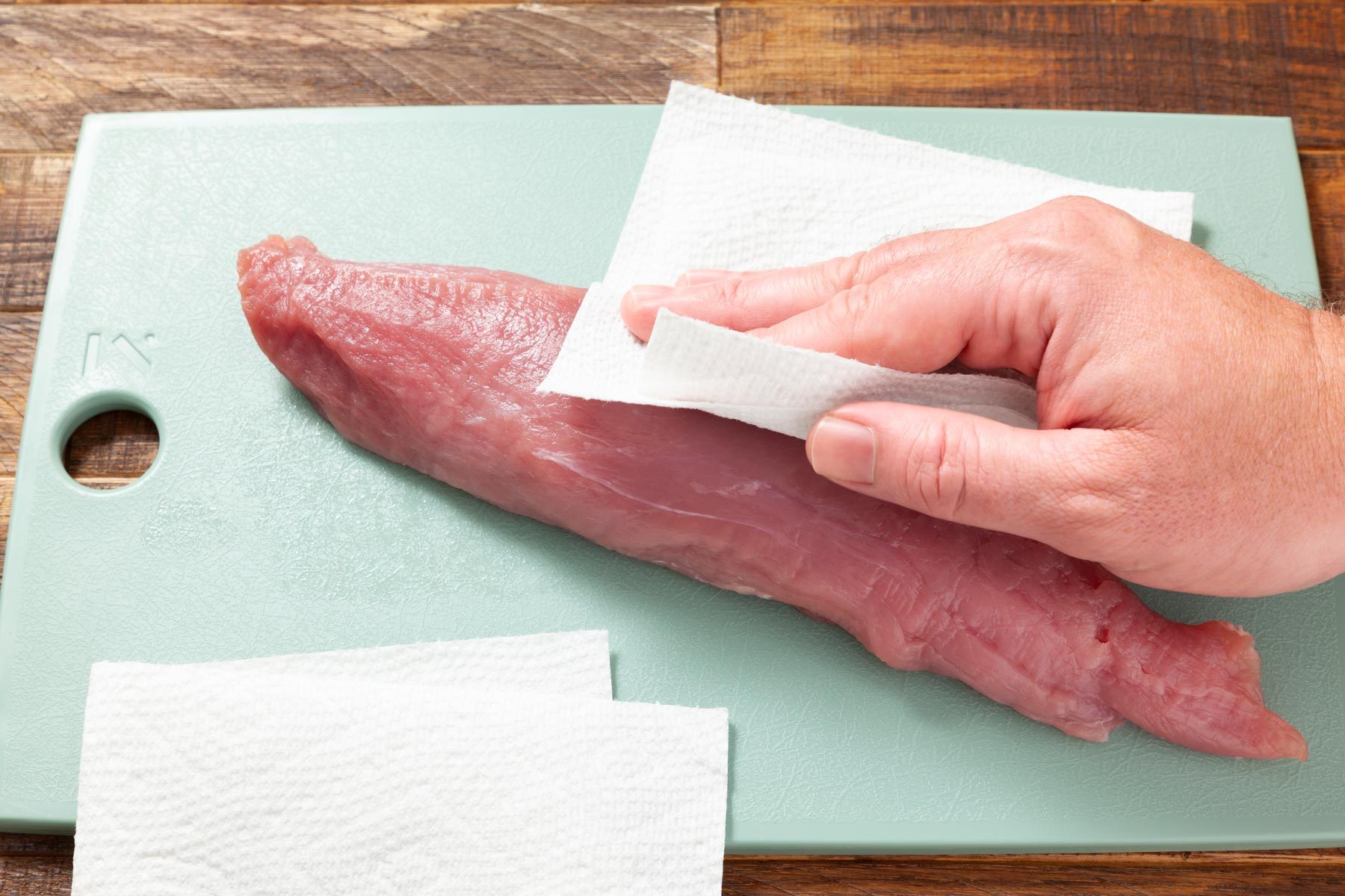A Person Cleaning Meat on a Cutting Board