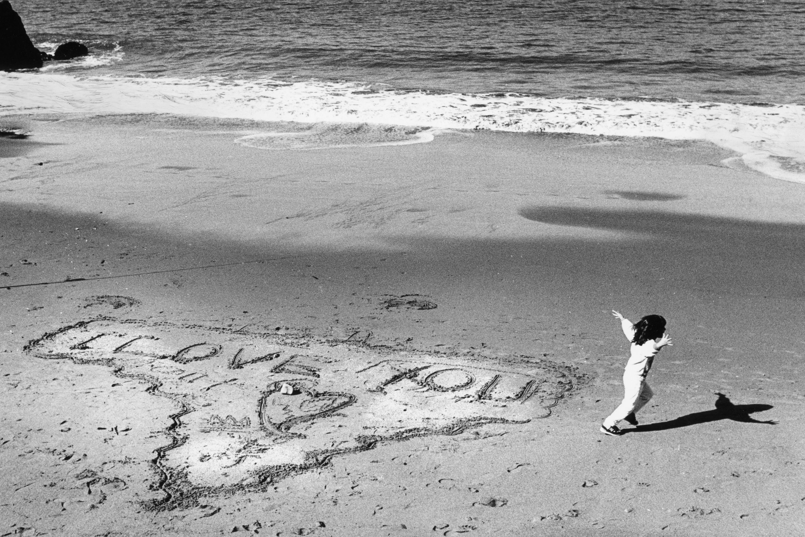 Isra Jacoby, 5 draws a valentine message in the sand at China Beach on Valentine