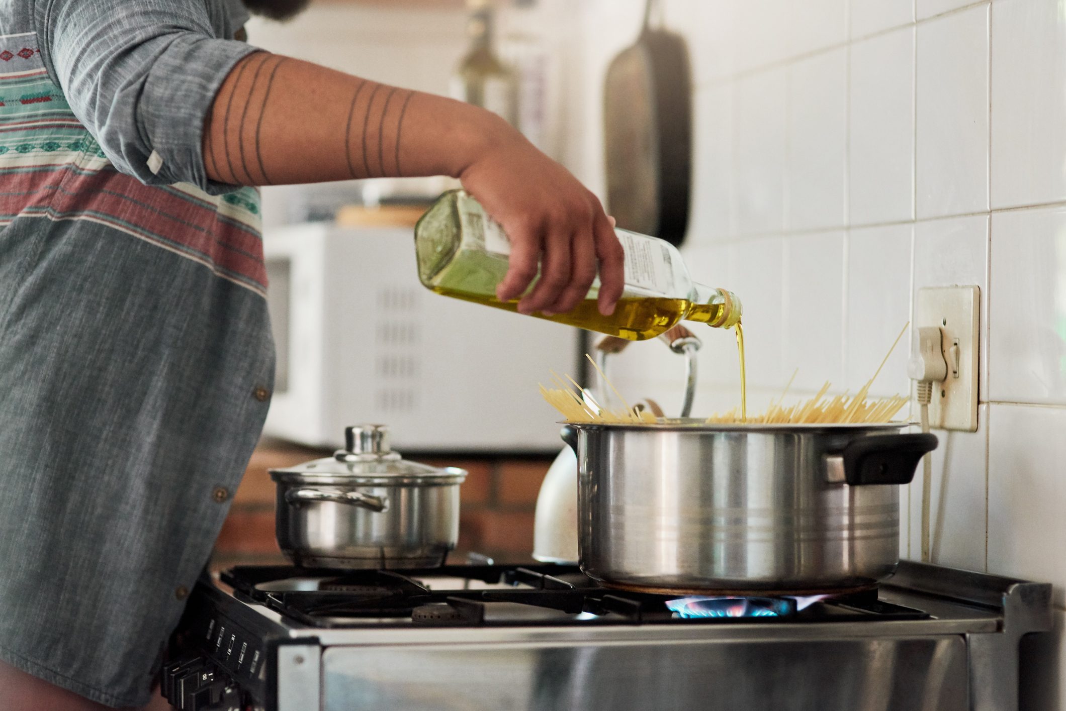 Shot of an unrecognizable person cooking pasta in their kitchen