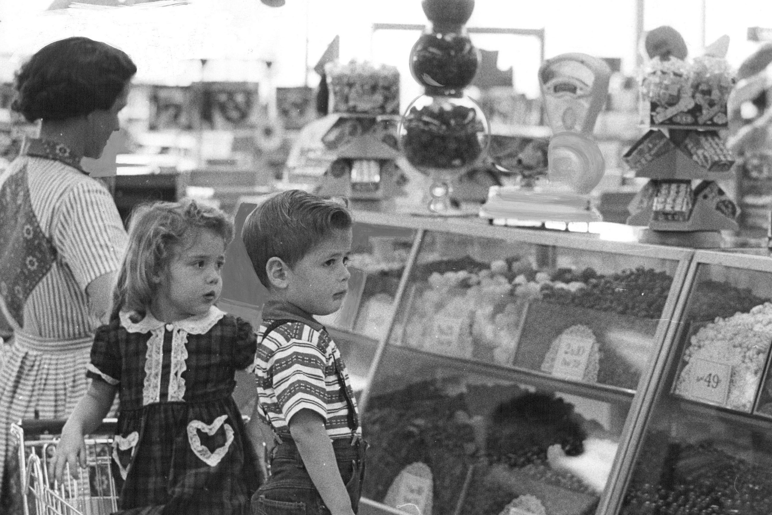 Mrs. C.F. Decker, 1745 S. Shoshone St., and her children, Cassandra, 4, and Brent, 3, think the candy is dandy in the Hested store display of Valentine