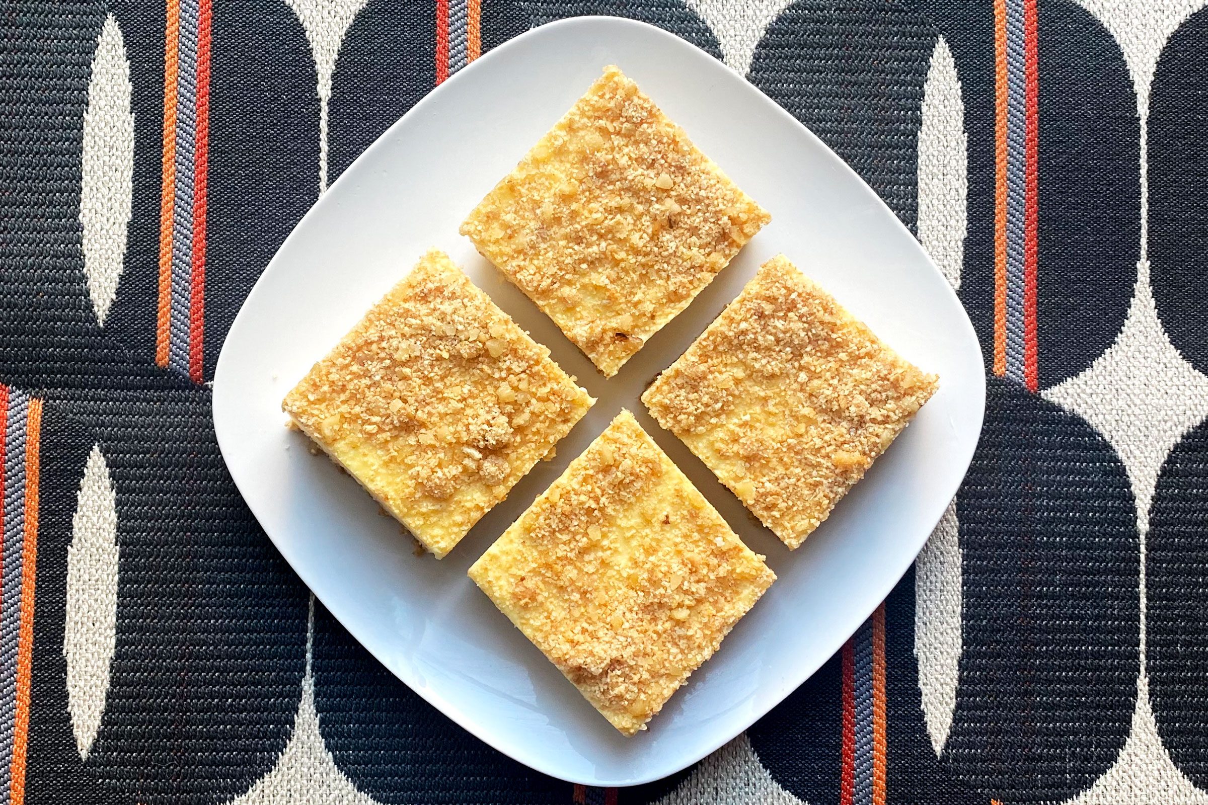 Creamy Pineapple Squares finished product on white plate sitting atop a retro tablecloth