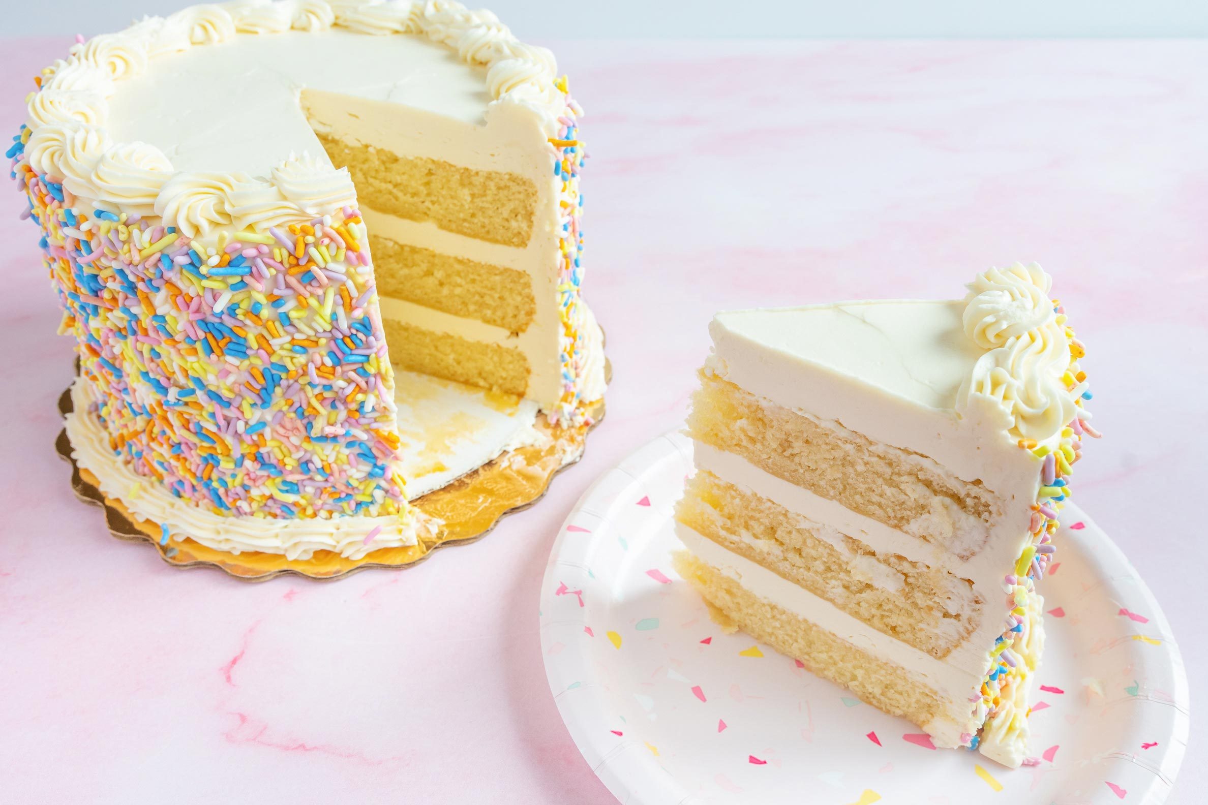 cake from whole foods with a slice cut from it on pink background