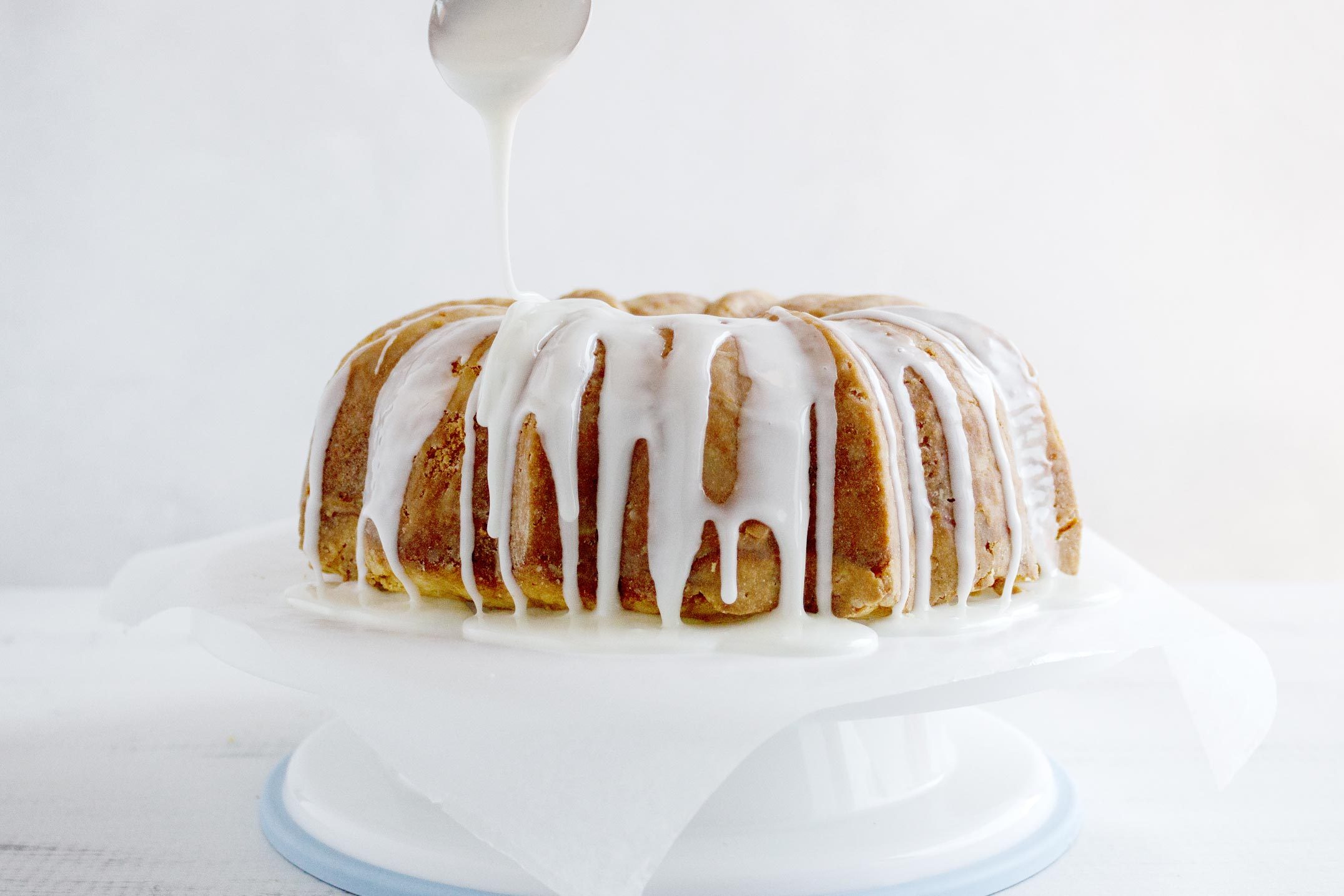 frosting a bundt cake with vanilla glaze