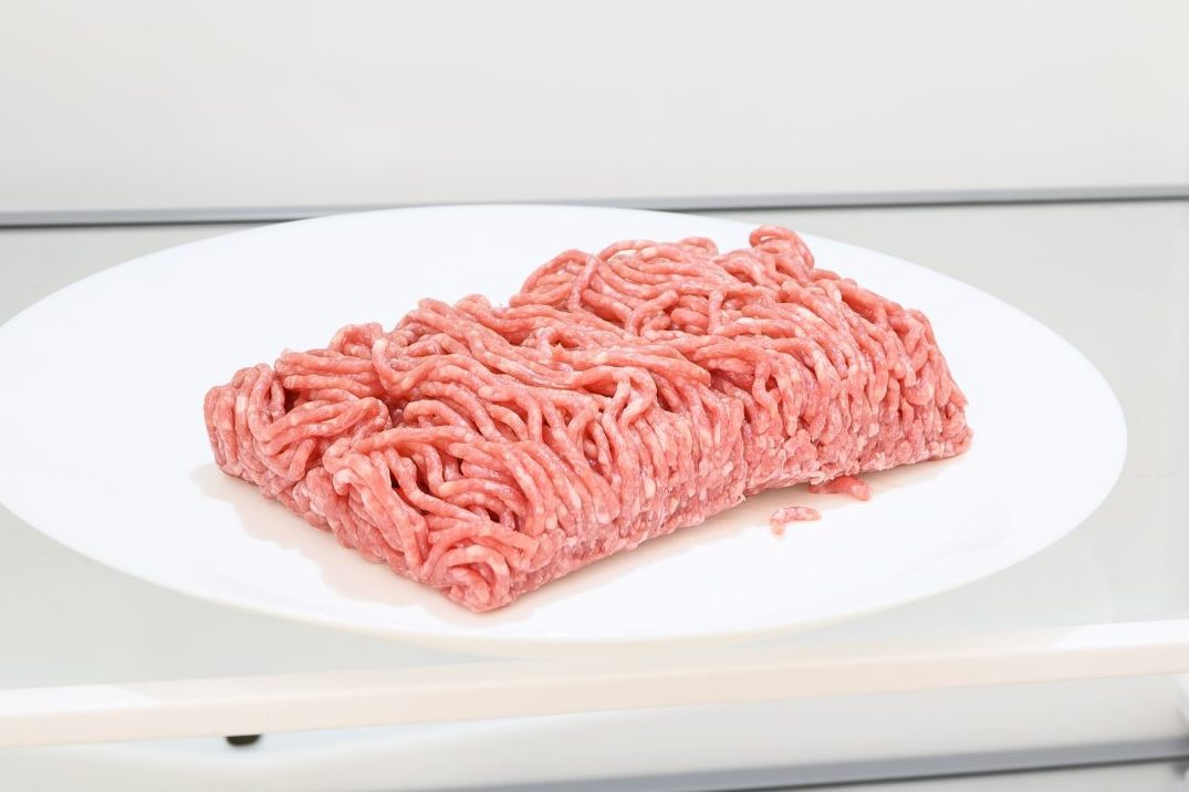 Meat in a plate on a white plate inside fridge.