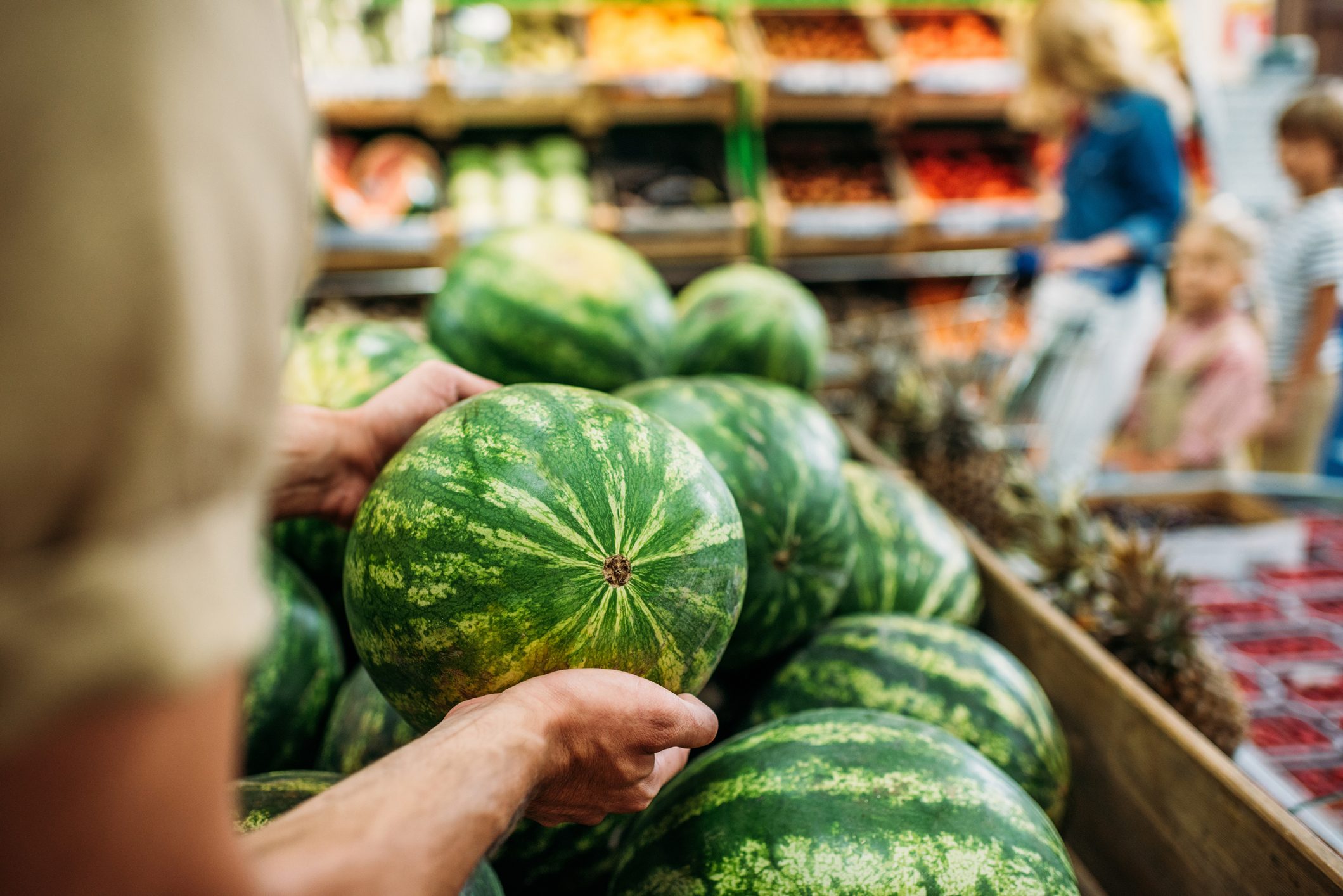 woman picking watermelon in grocery shop