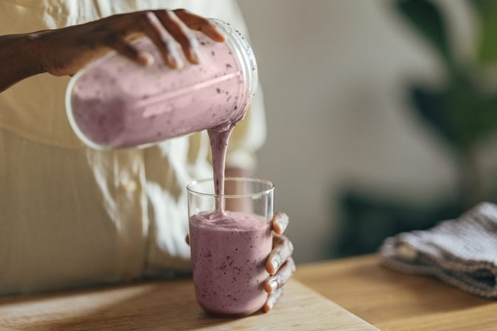 woman pouring a fruit smoothing into a glass