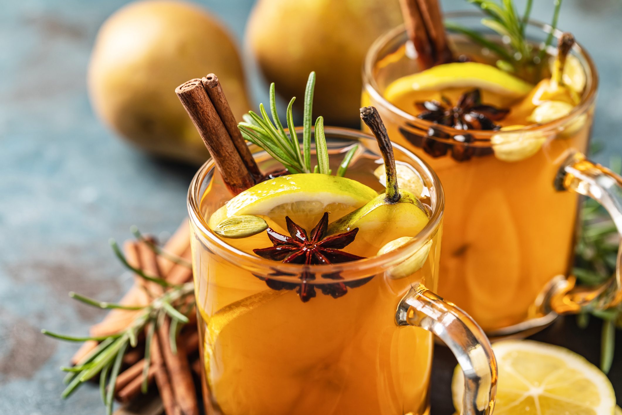 Hot drink cocktail for New Year, Christmas, winter or autumn holidays. Toddy. Mulled pear cider or spiced tea or grog with lemon, pear, cinnamon, anise, cardamom, rosemary.