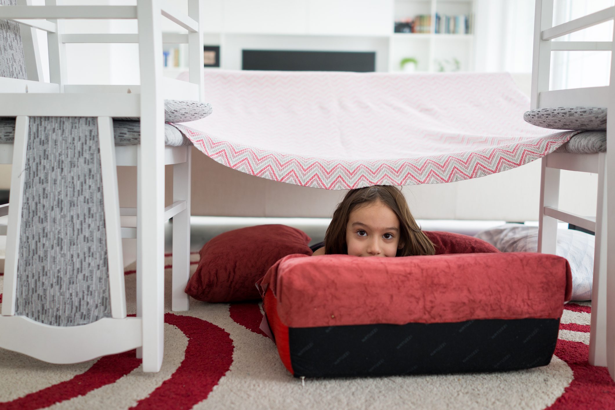 Child building with pillows and chairs