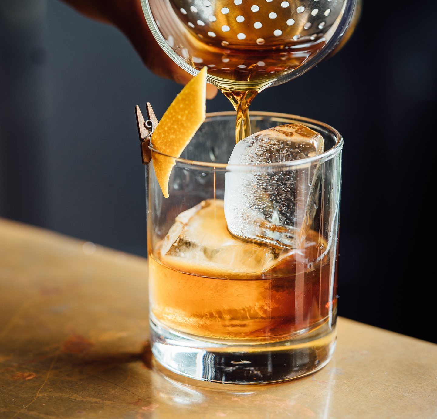 Closeup Glass with Amber Whiskey or Brandy Alcohol Drink with Ice in Cocktail Bar