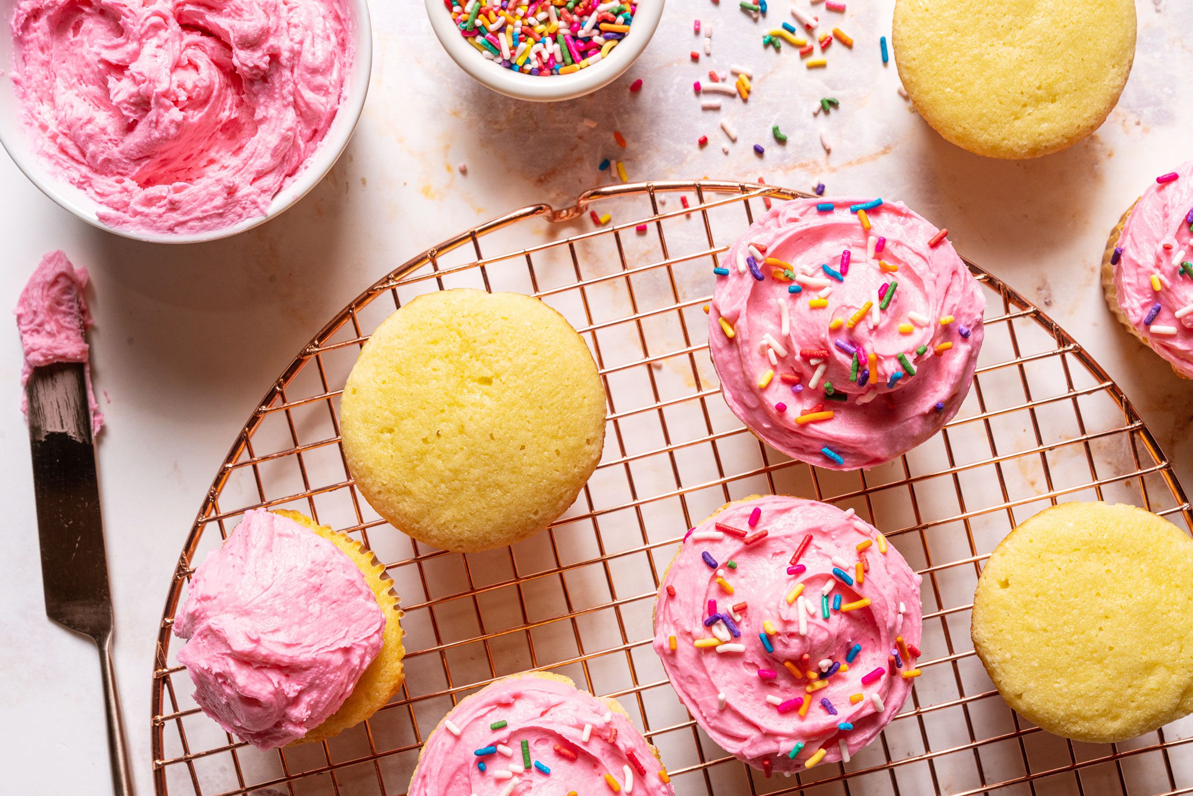frosting Magnolia Cupcakes with pink frosting and sprinkles, top view