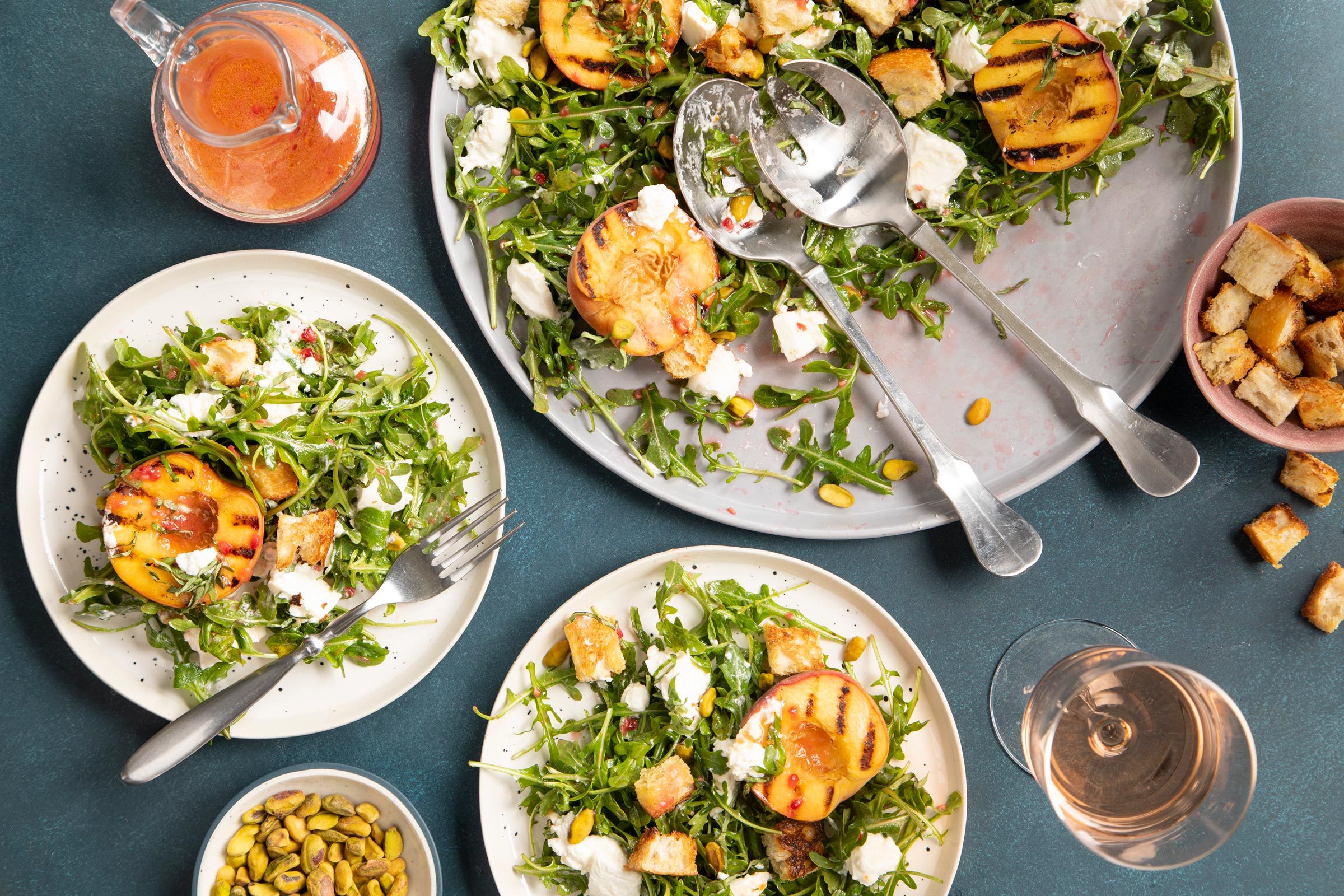 Peach Burrata salad divided onto smaller plates on a blue table background