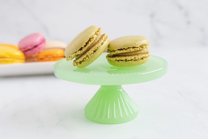 Pistachio macaroon on a green plate with a stand