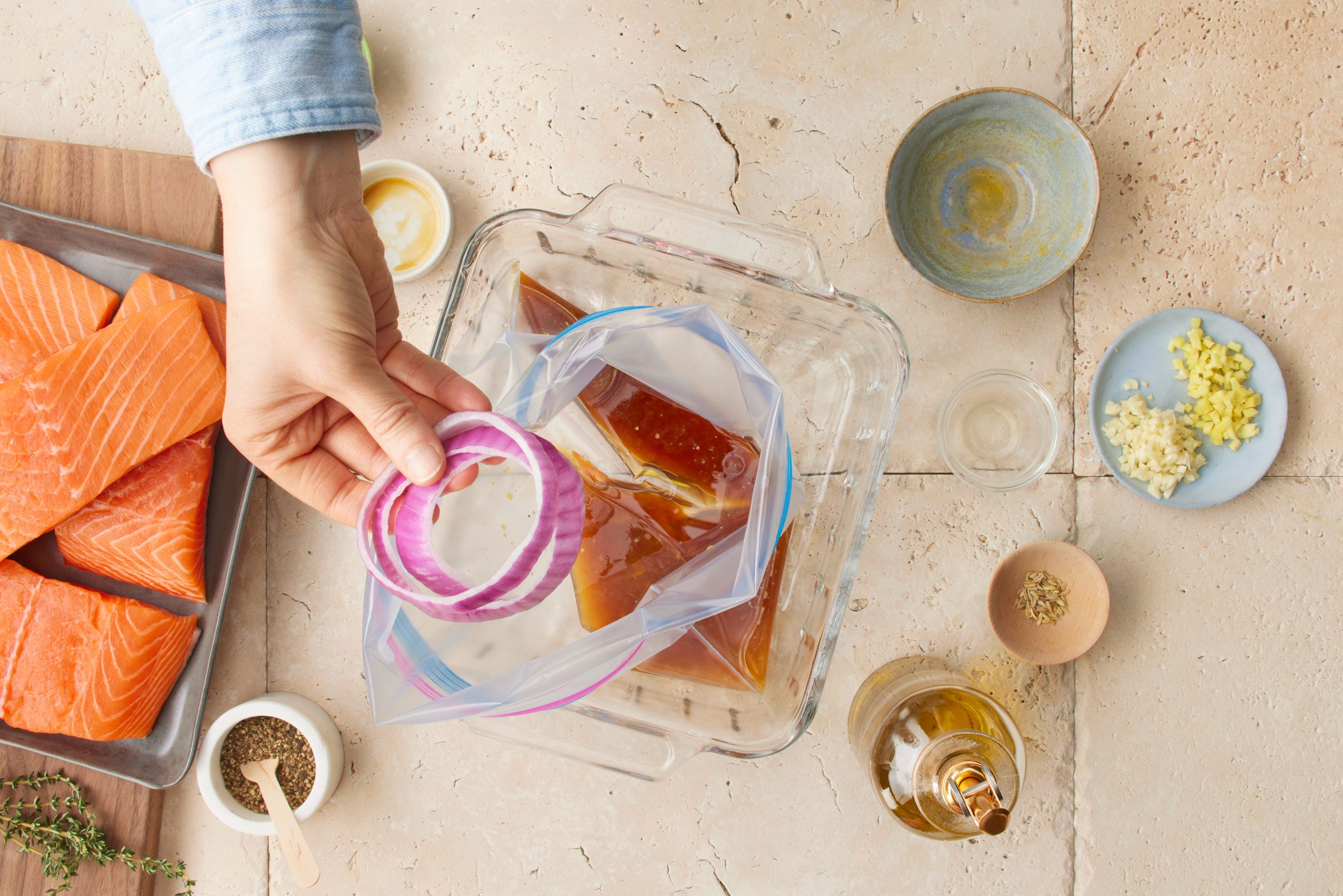 hand placing an onion in a bag with marinade for salmon