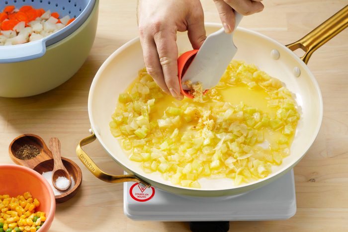 Vegan Potpie Showing Garlic Being Added To Potato Carrot Mixture.