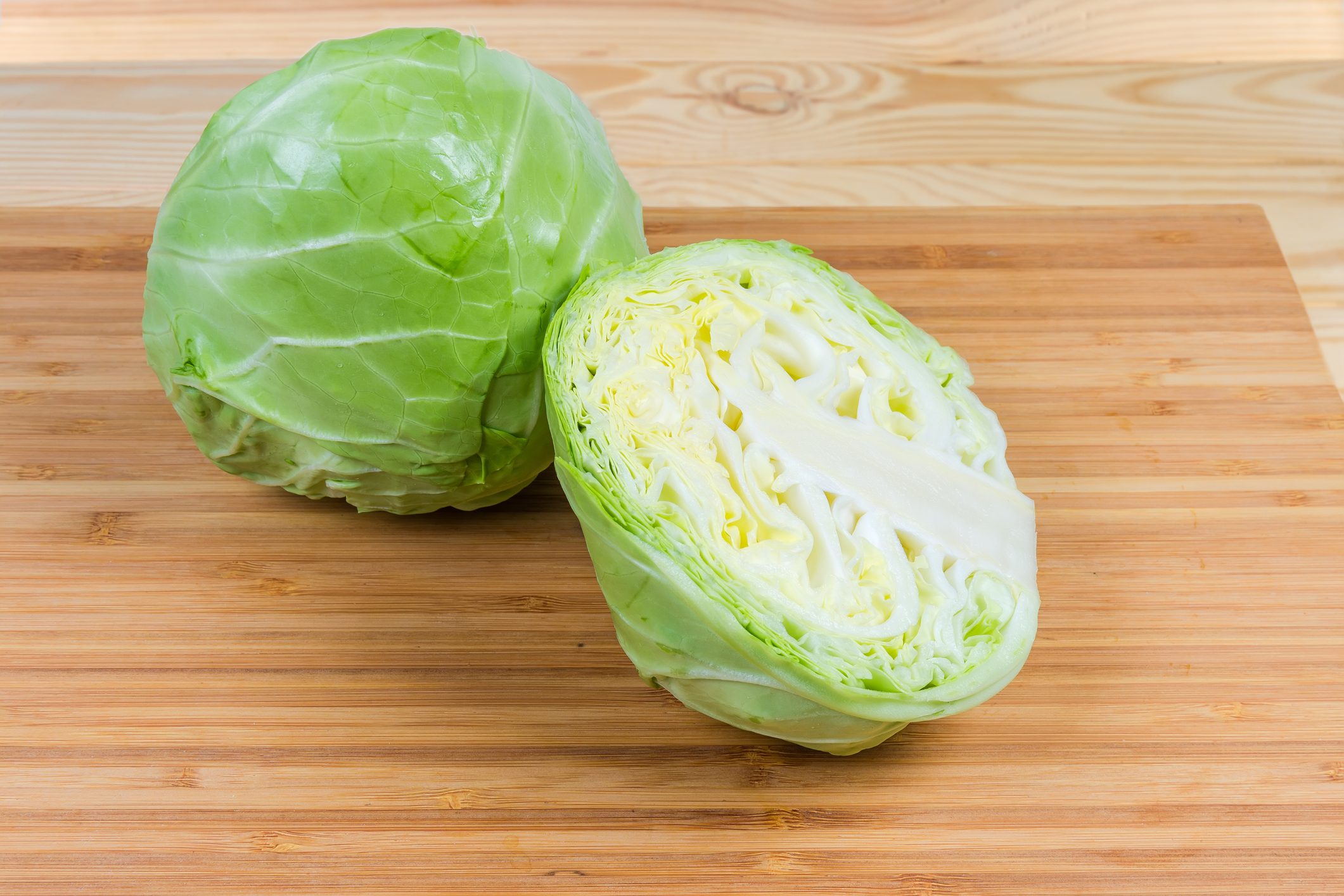 Whole and half of young cabbage head on cutting board