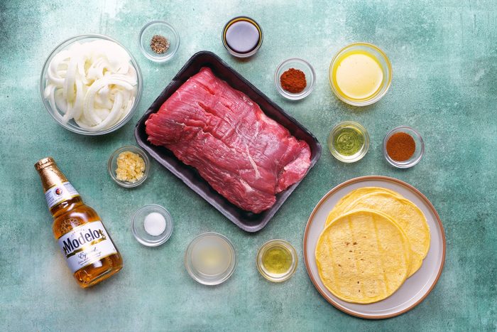 top view of ingredients for Slow-Cooker Carne Asada on a teal background