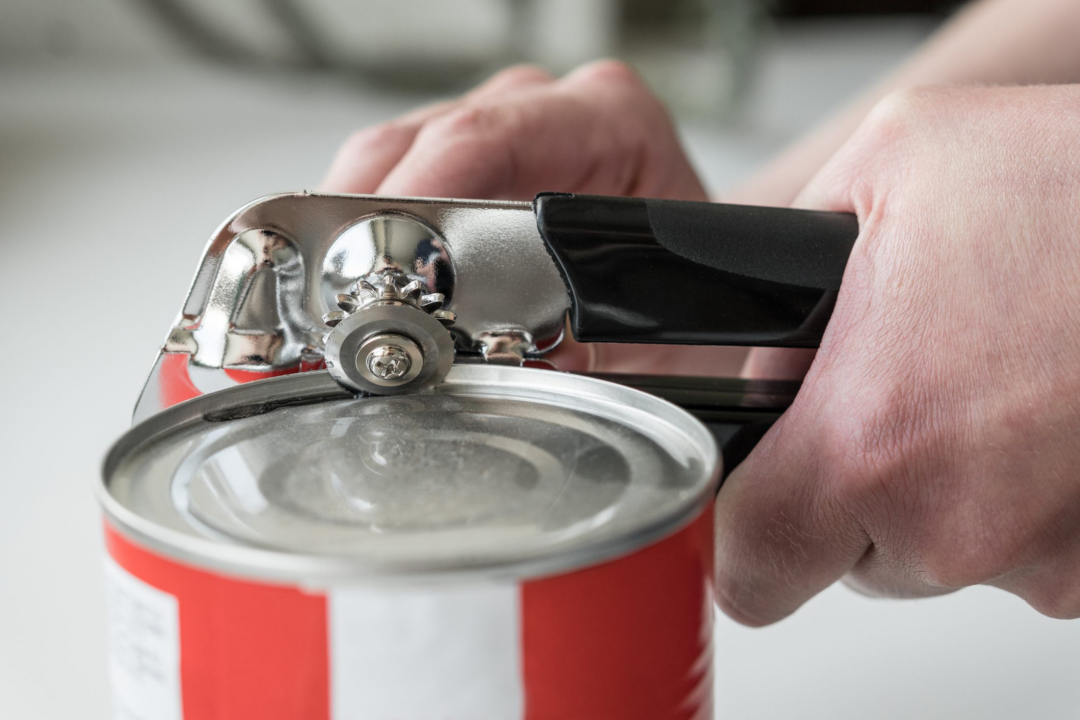hands using a canopener to open canned potatoes