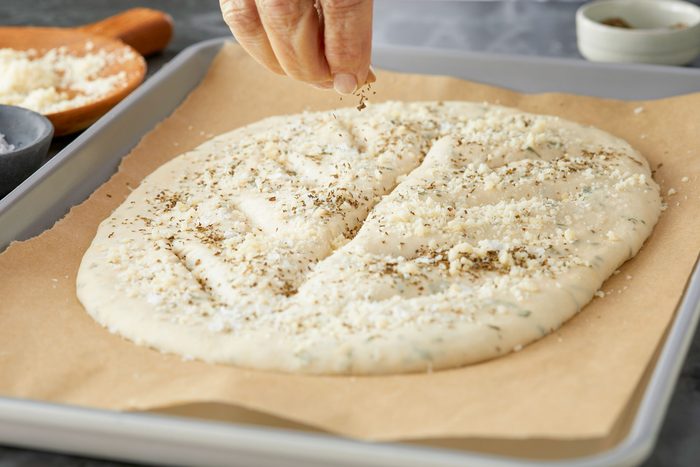 Sprinkling Dried Basil on a Fougasse Dough