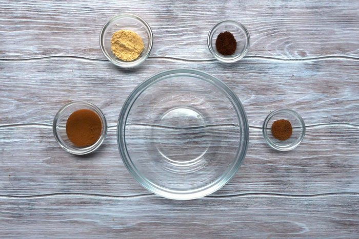 Spices in small bowls with an empty large bowl in center
