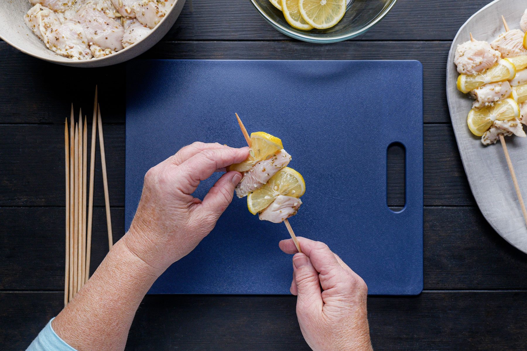 Threading the chicken pieces and the lemon slices on the skewers.