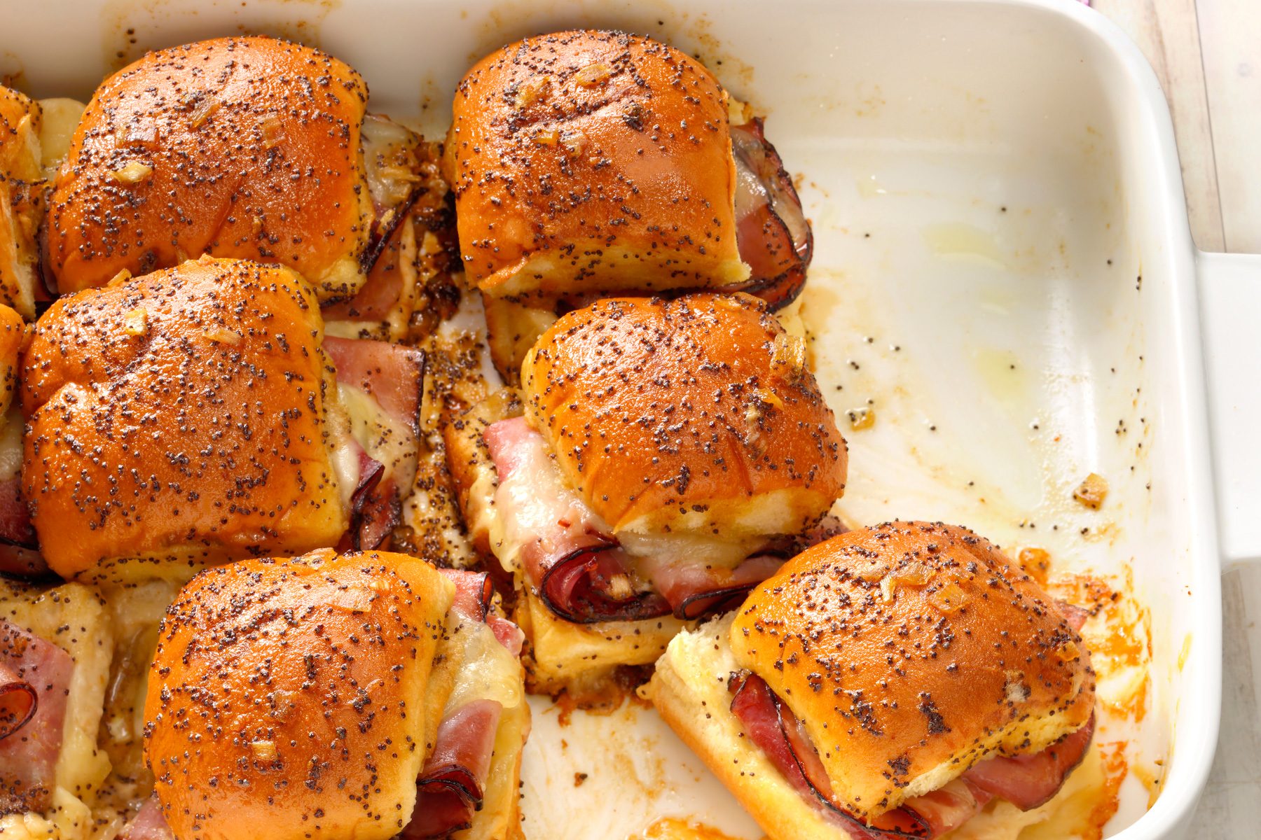A tray of swiss slider with a ham and cheese topping