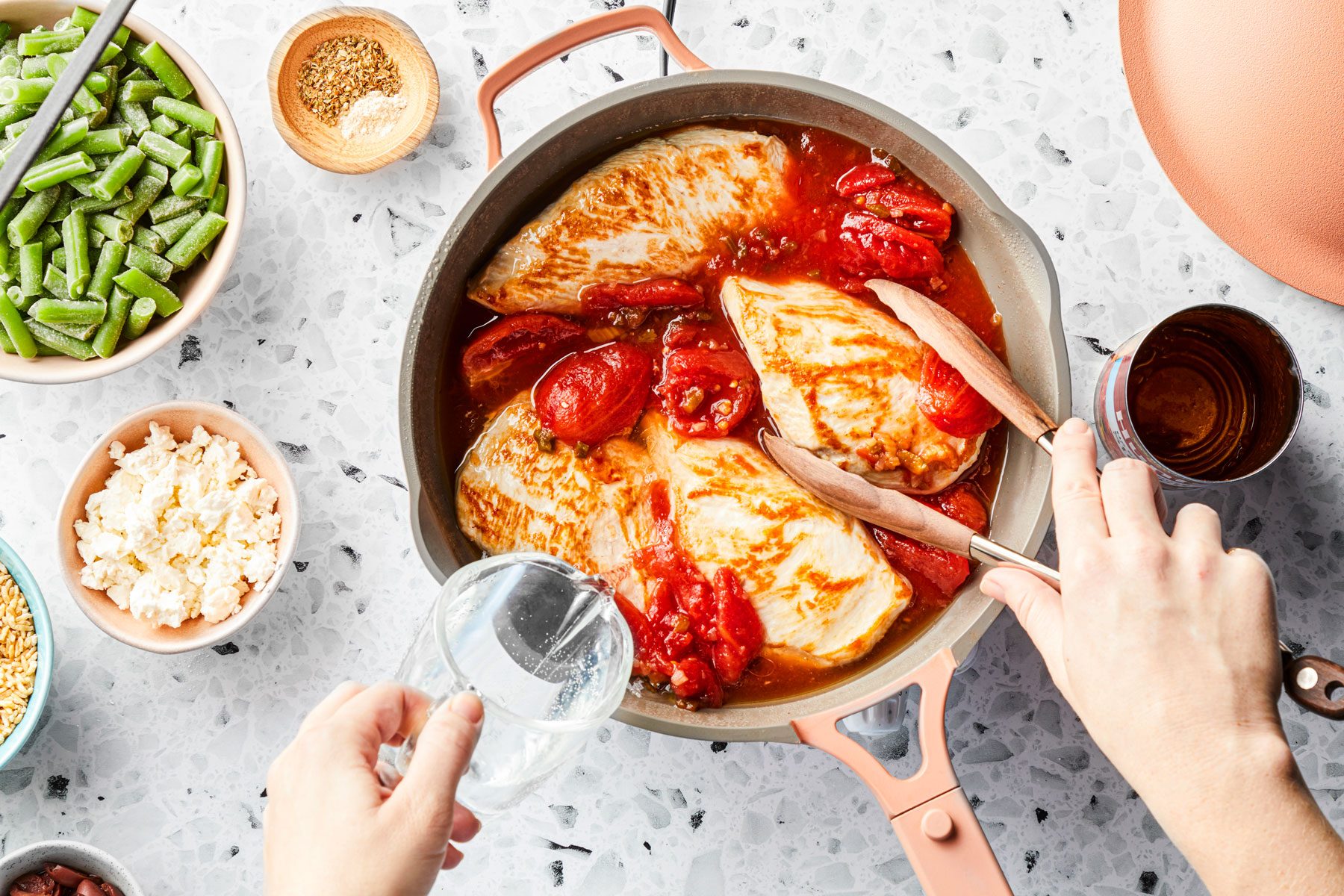 Chicken breast and tomatoes mixed in a large pan 