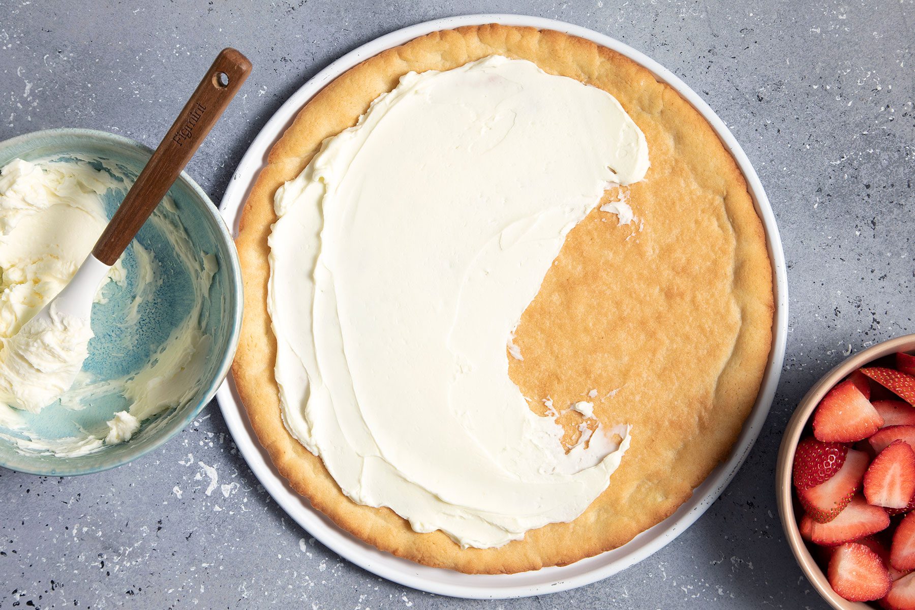 Spreading cream cheese on baked dough