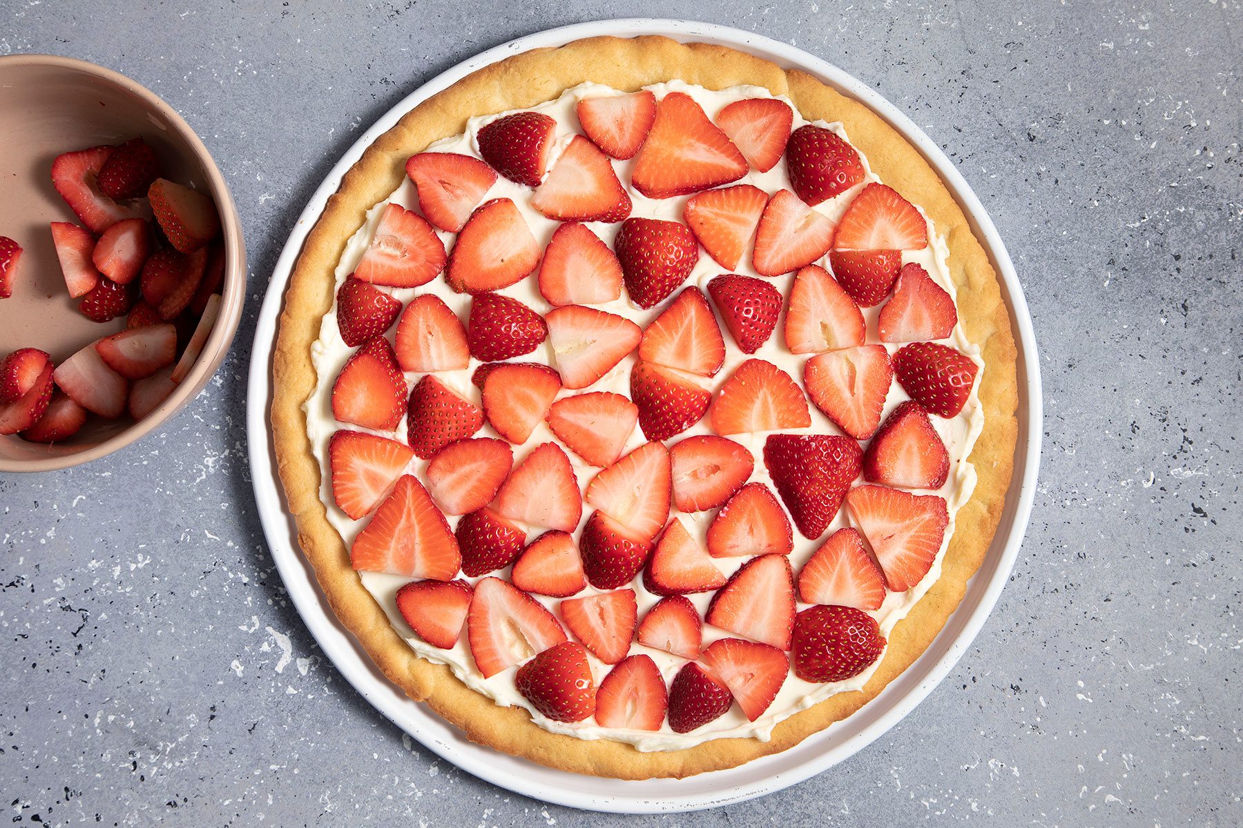 Sliced strawberries on baked pizza dough