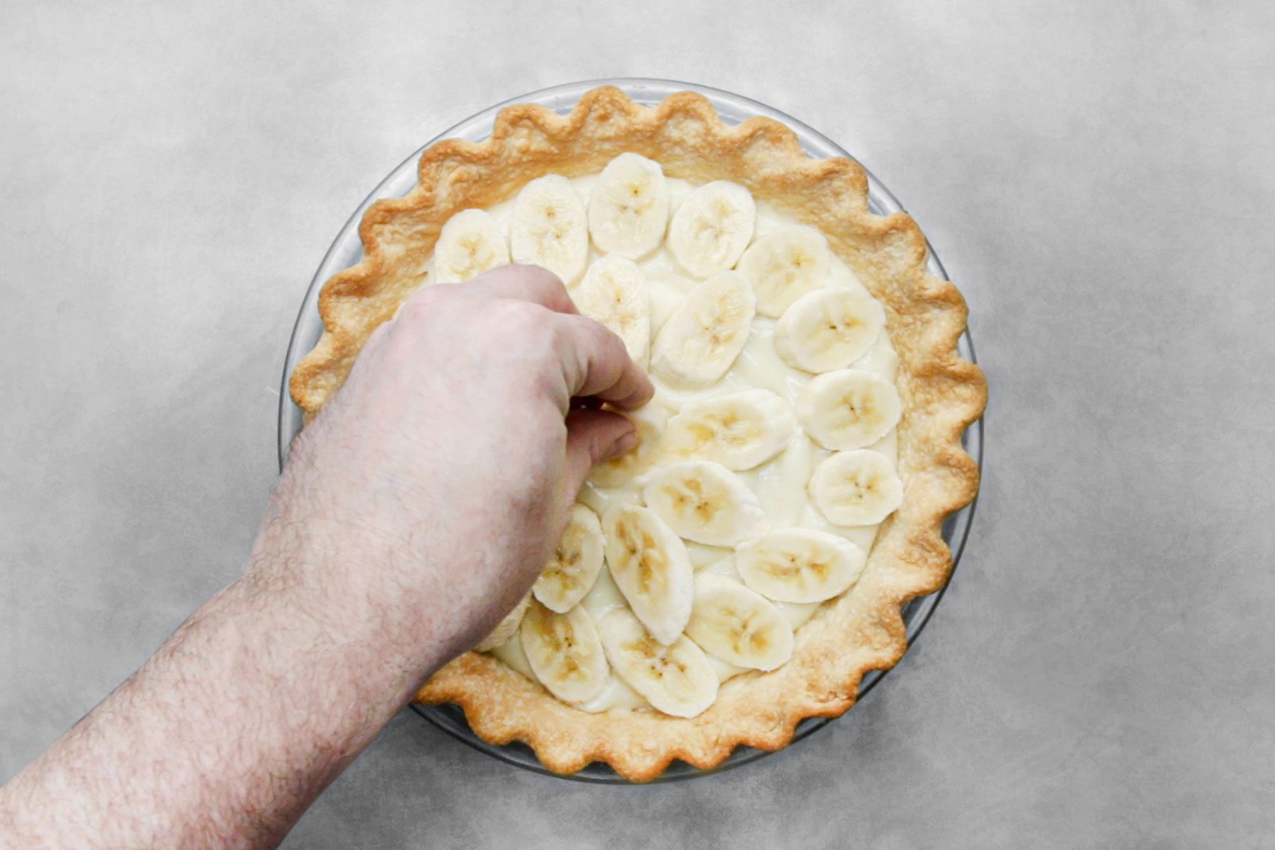 Arranging the sliced bananas over custard filled pie