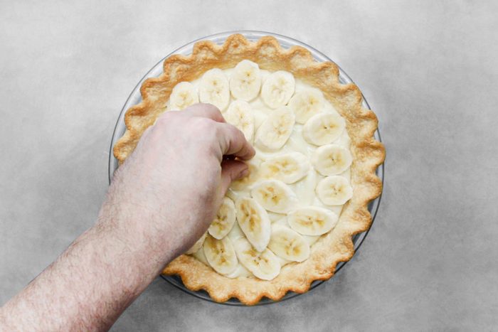 Arranging the sliced bananas over custard filled pie