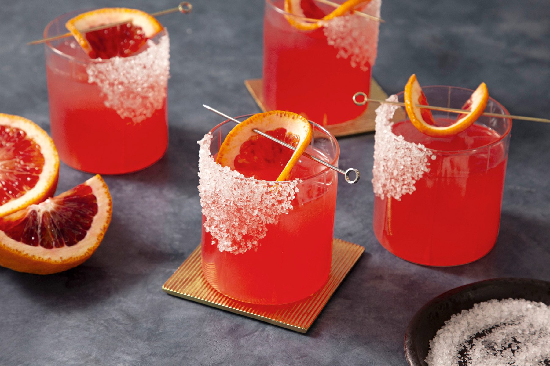 A group of glasses of blood orange margarita with orange slices.