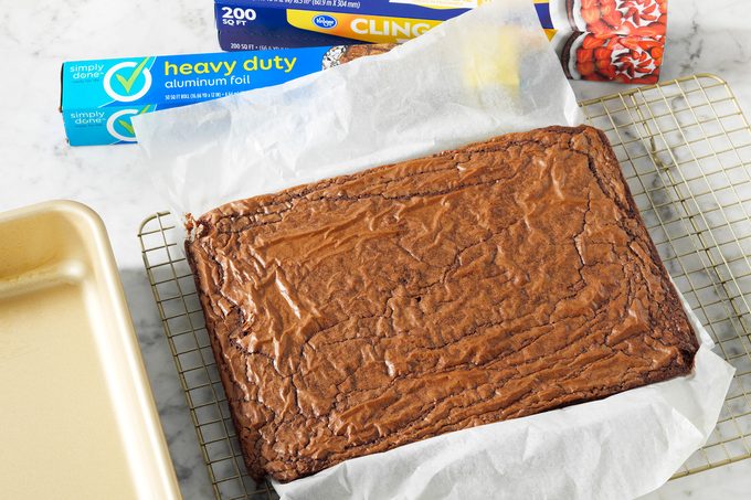 A full pan of brownies cooling on a metal rack before being prepped further for freezing