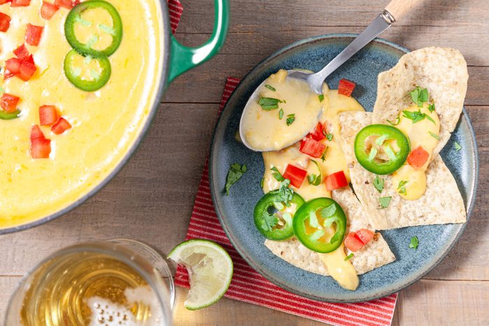 Chili Con Queso served with chips in a plate with a drink