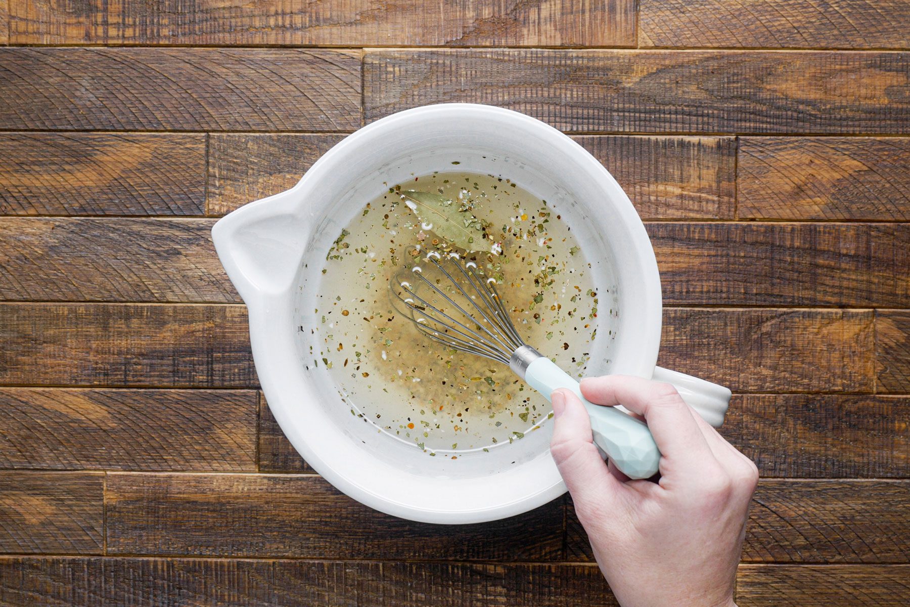 Mixinng together the water, garlic, bay leaf and other ingredients in a small bowl