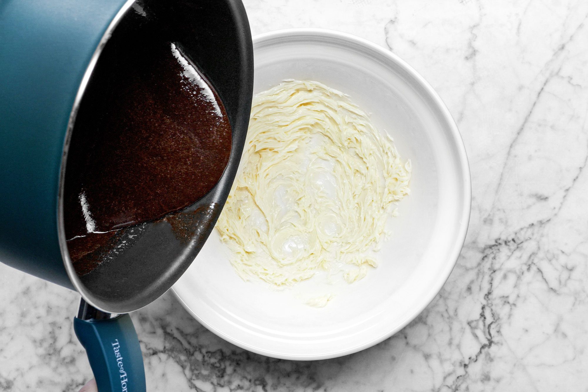 pouring melted chocolate into a large white bowl , marble background