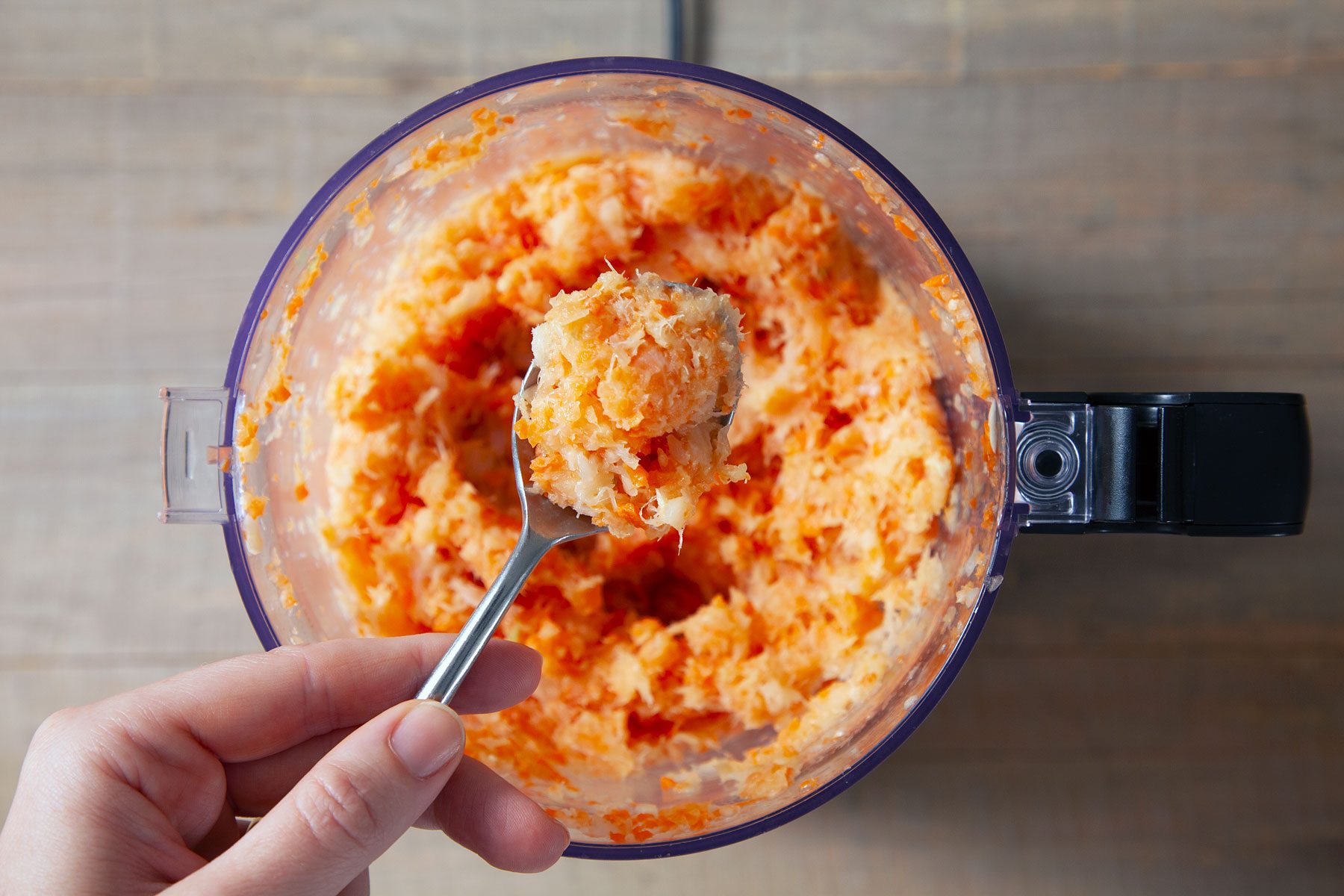 A person holding a spoon full of Mixture