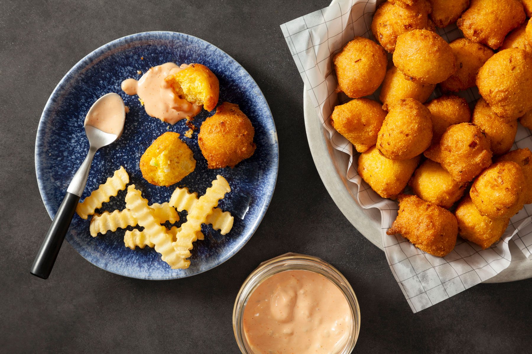 Hush Puppies served in a small plate with fries and sauce.