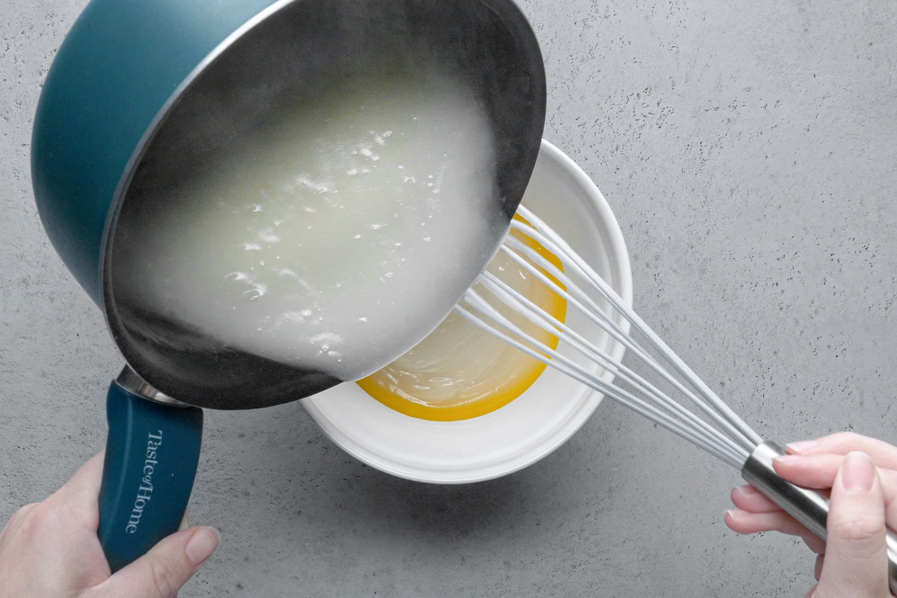 Mixture being poured in beaten egg yolks in a small bowl