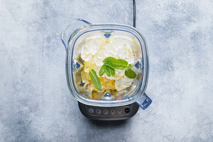 Yogurt, mango, ice, sugar, mint combined in a blender to make mango lassi