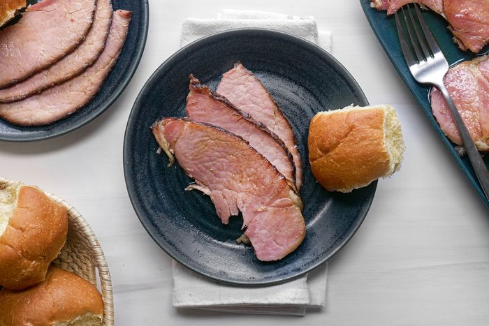Maple Glazed Ham served in a plate with a bread bun on a white table