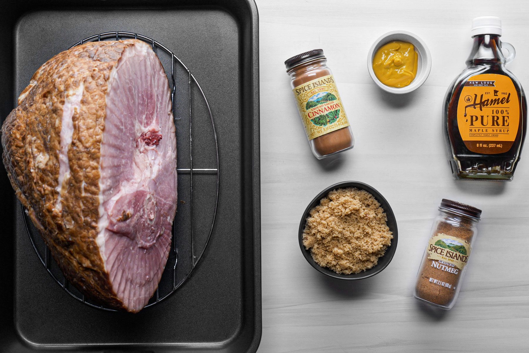 Spiral ham on a black tray and other ingredients put on a a white table
