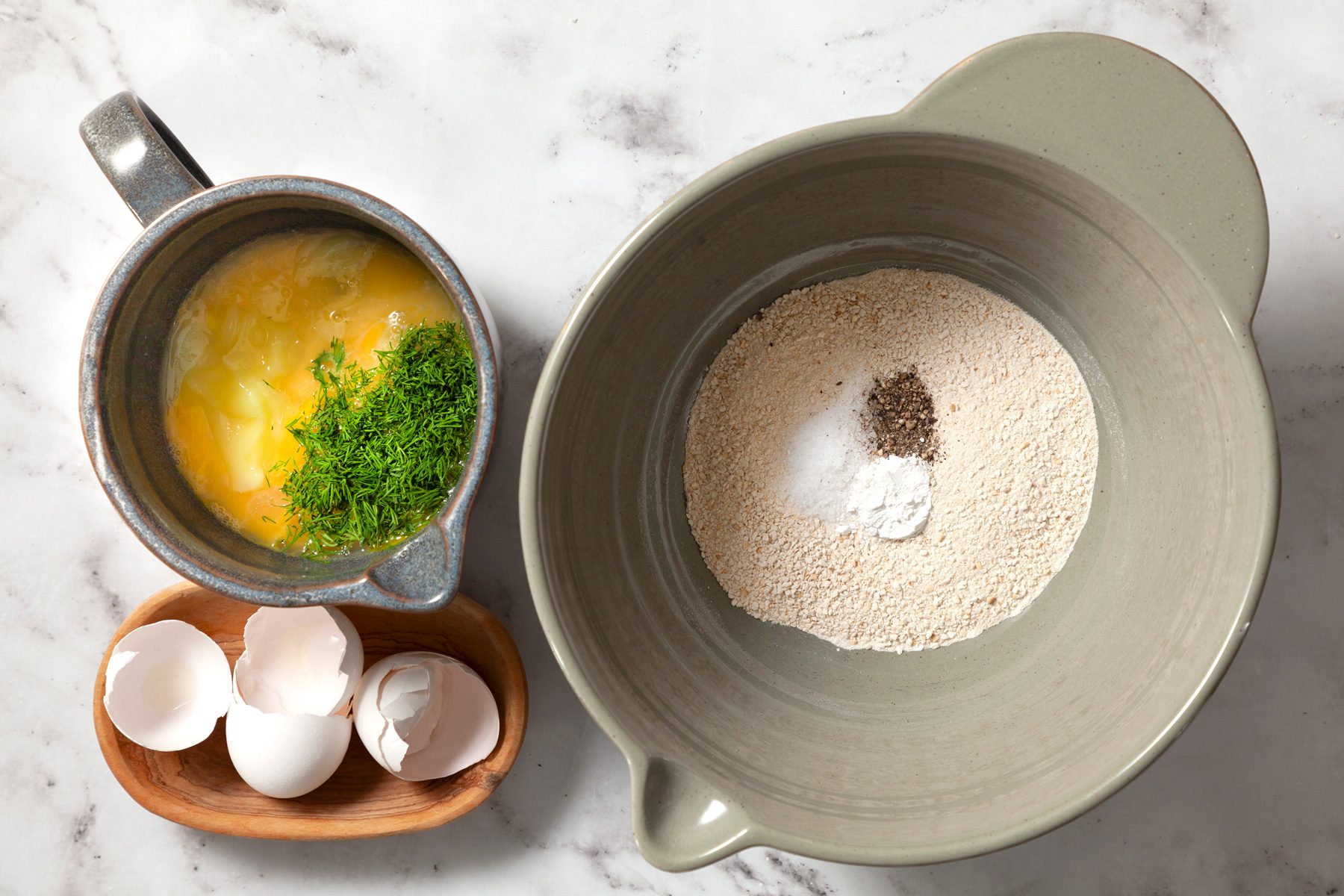two mixing bowls, one with dry ingredients and the other with eggs 