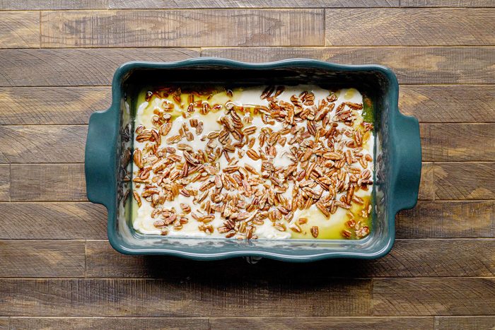 Pecans layers over batter in blue baking tray
