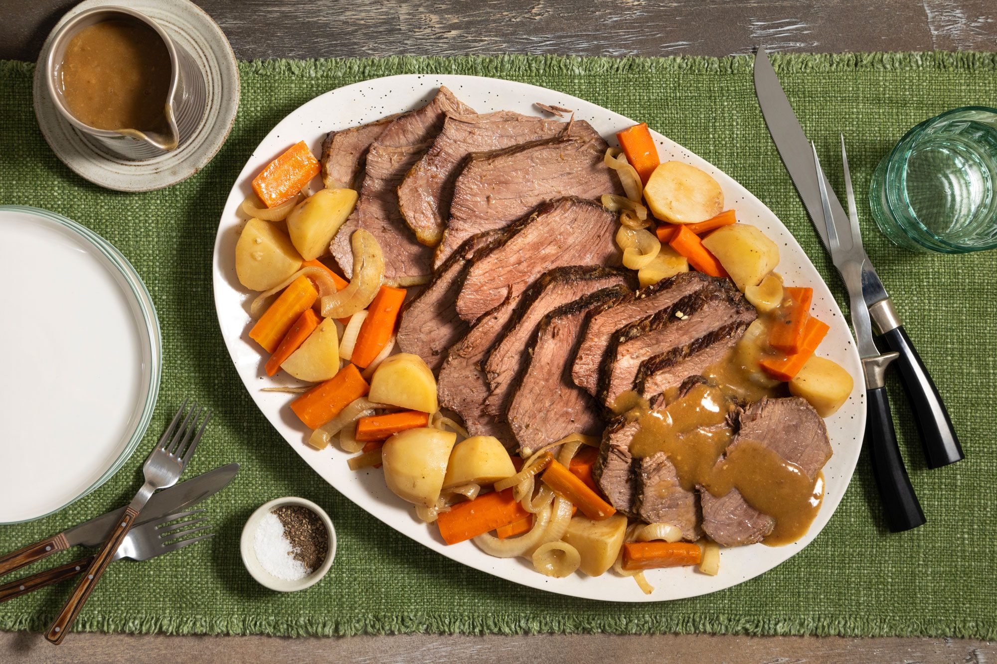 Slow Cooker Rump Roast Served in an Oval Shaped Plate on a Green Jute Cloth on a Wooden Surface