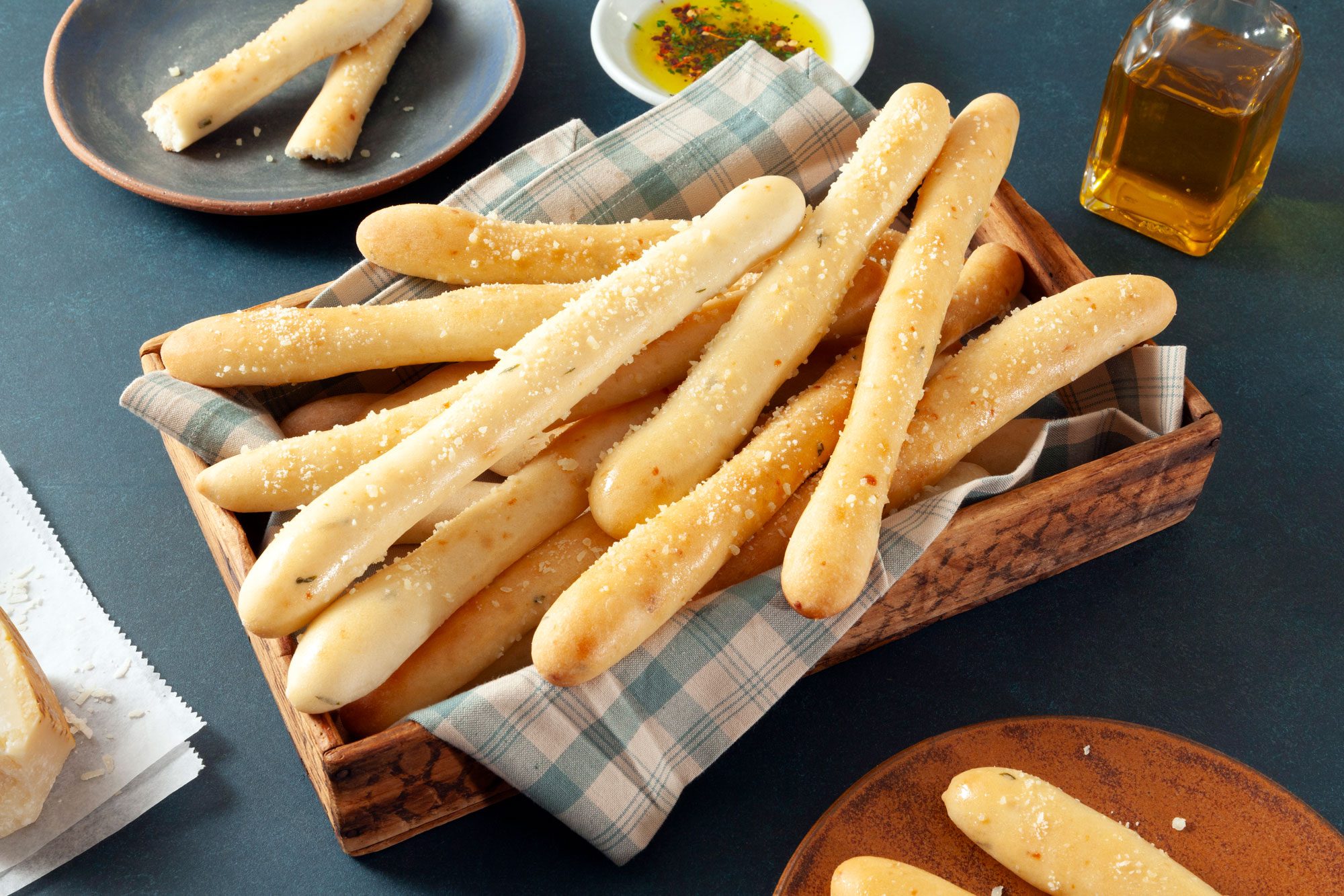 Soft Garlic Breadsticks Served in a Wooden Tray on Teal Surface