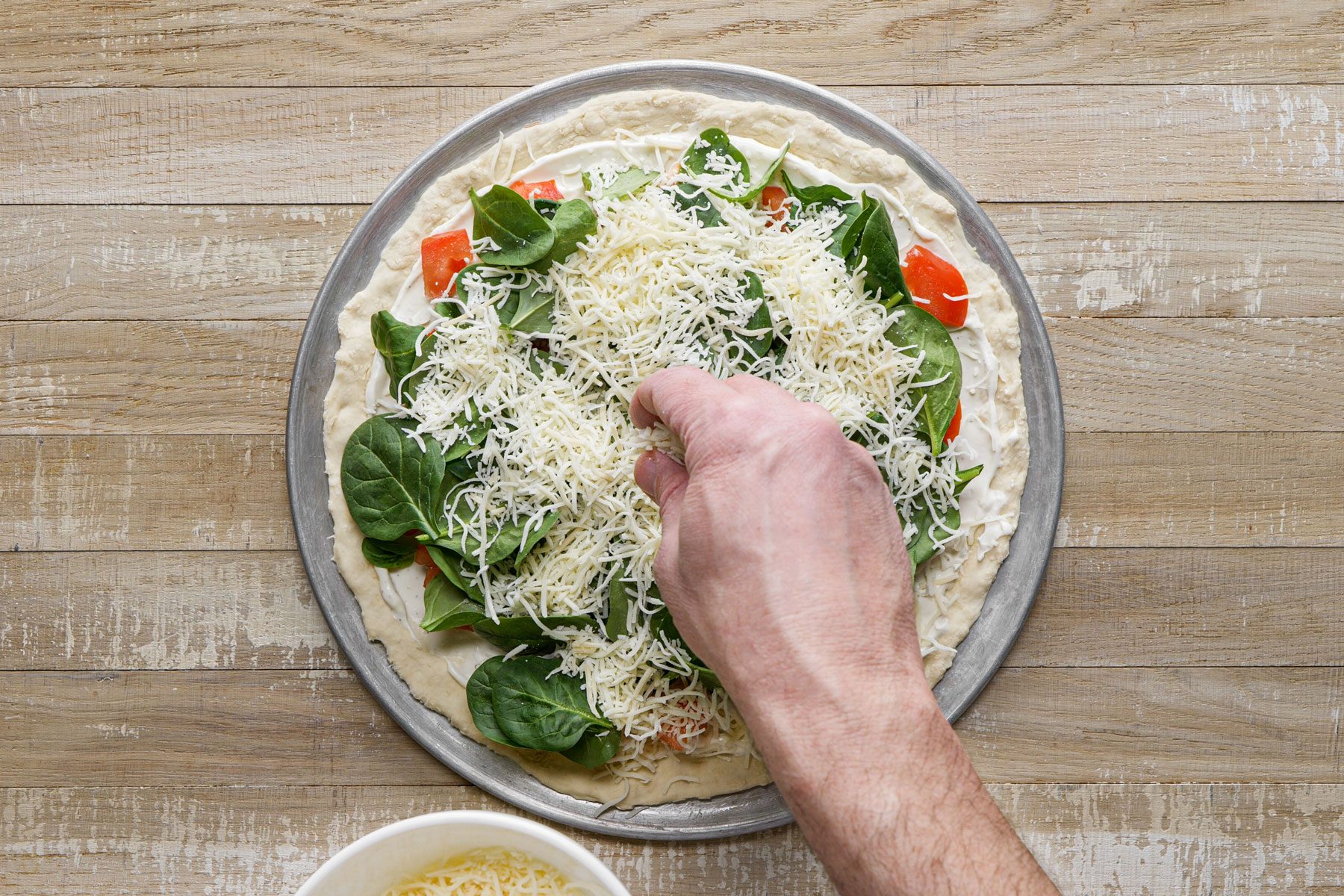 Layering the pizza with vegetables spinach and cheese 