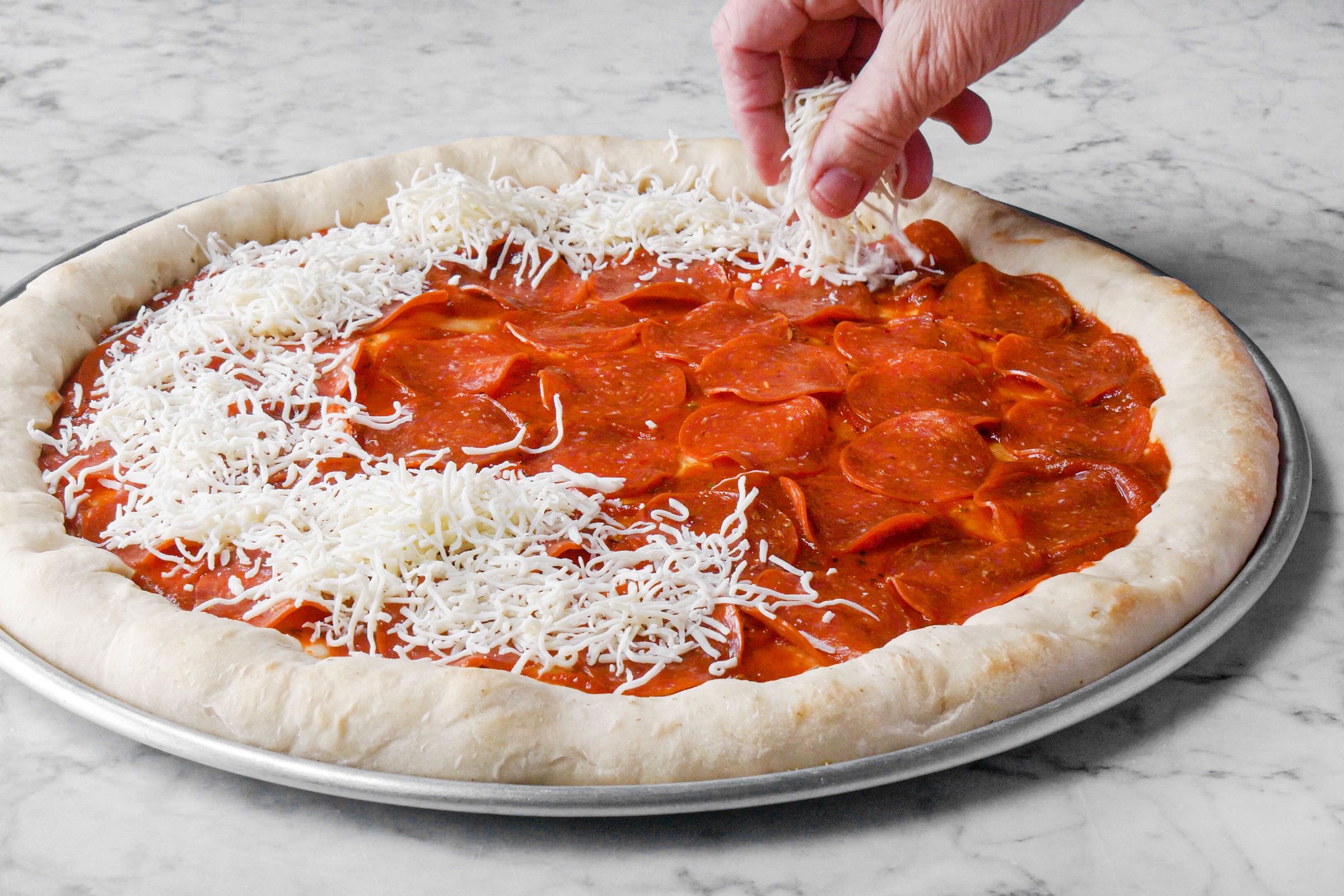 putting cheese on Pepperoni pizza 