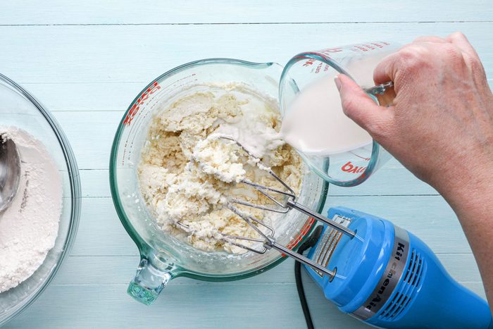 pouring milk into creamed butter