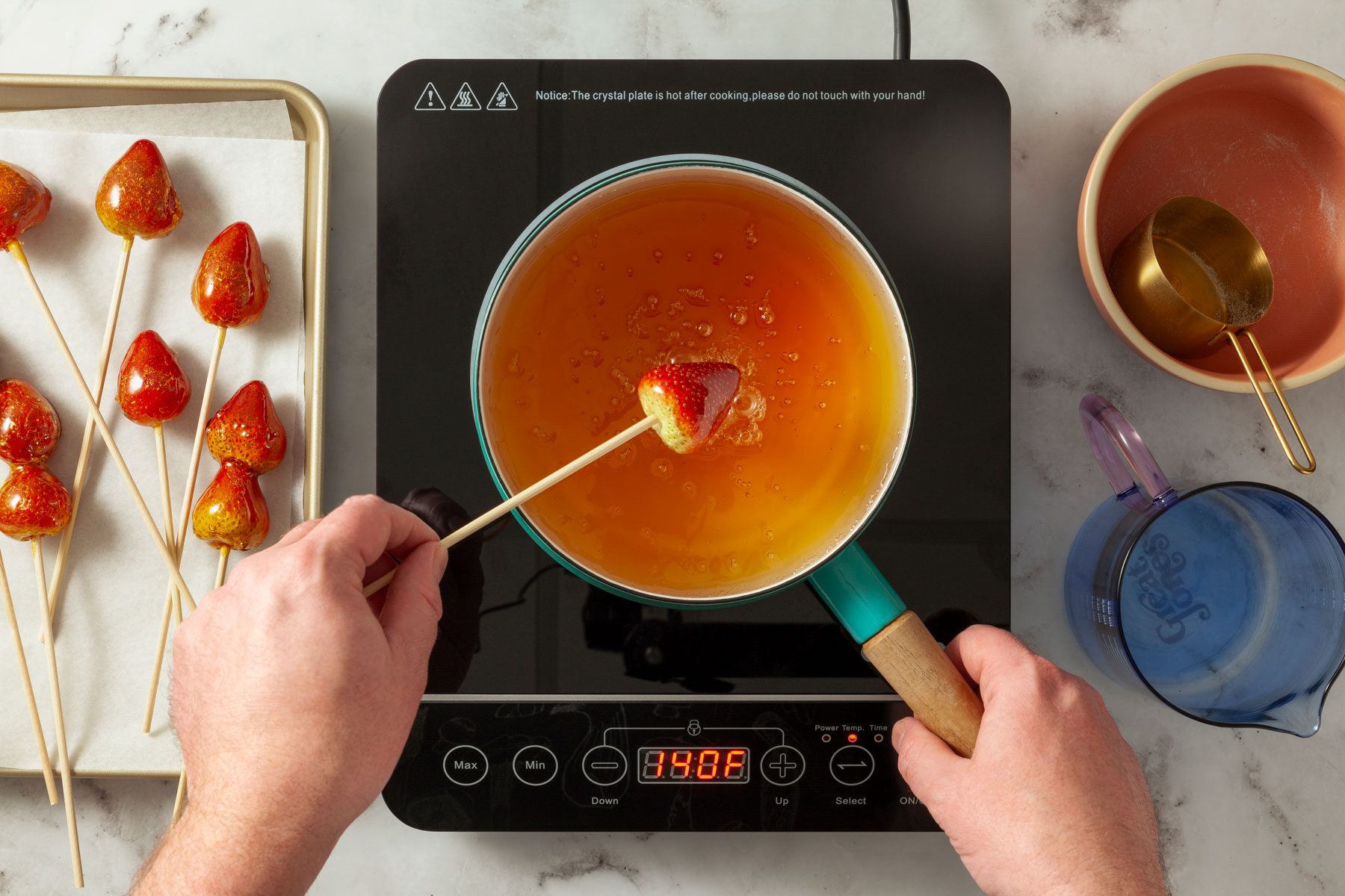 Dipping strawberry into the syrup in a large pan